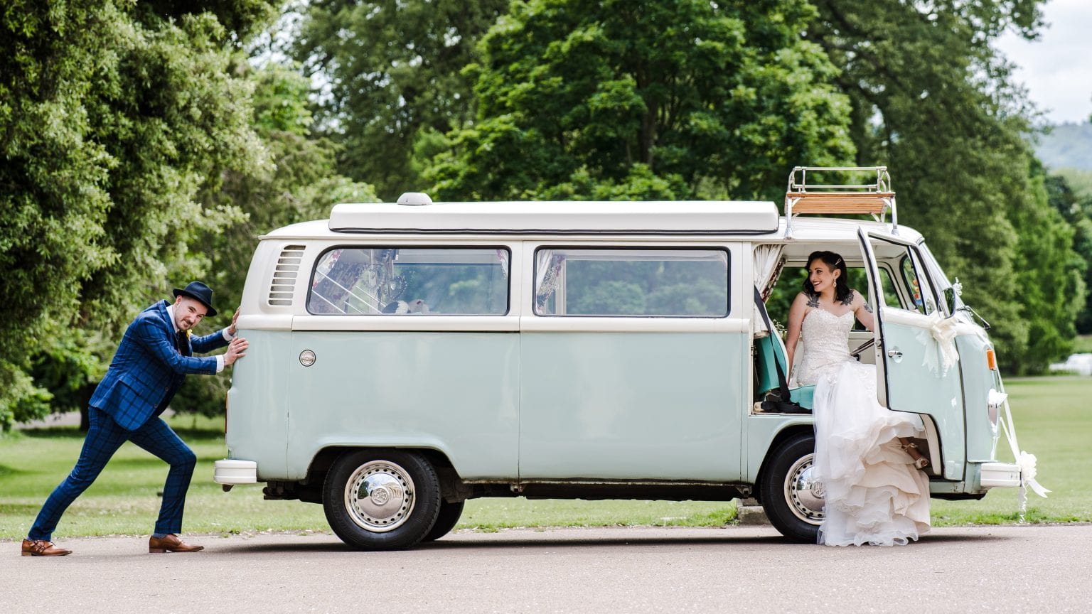 A newlywed couple pose in front of a stylish VW camper on their wedding day at Pittville Park in Cheltenham. The photographer is Pedge Olamaee of Pedge Photography