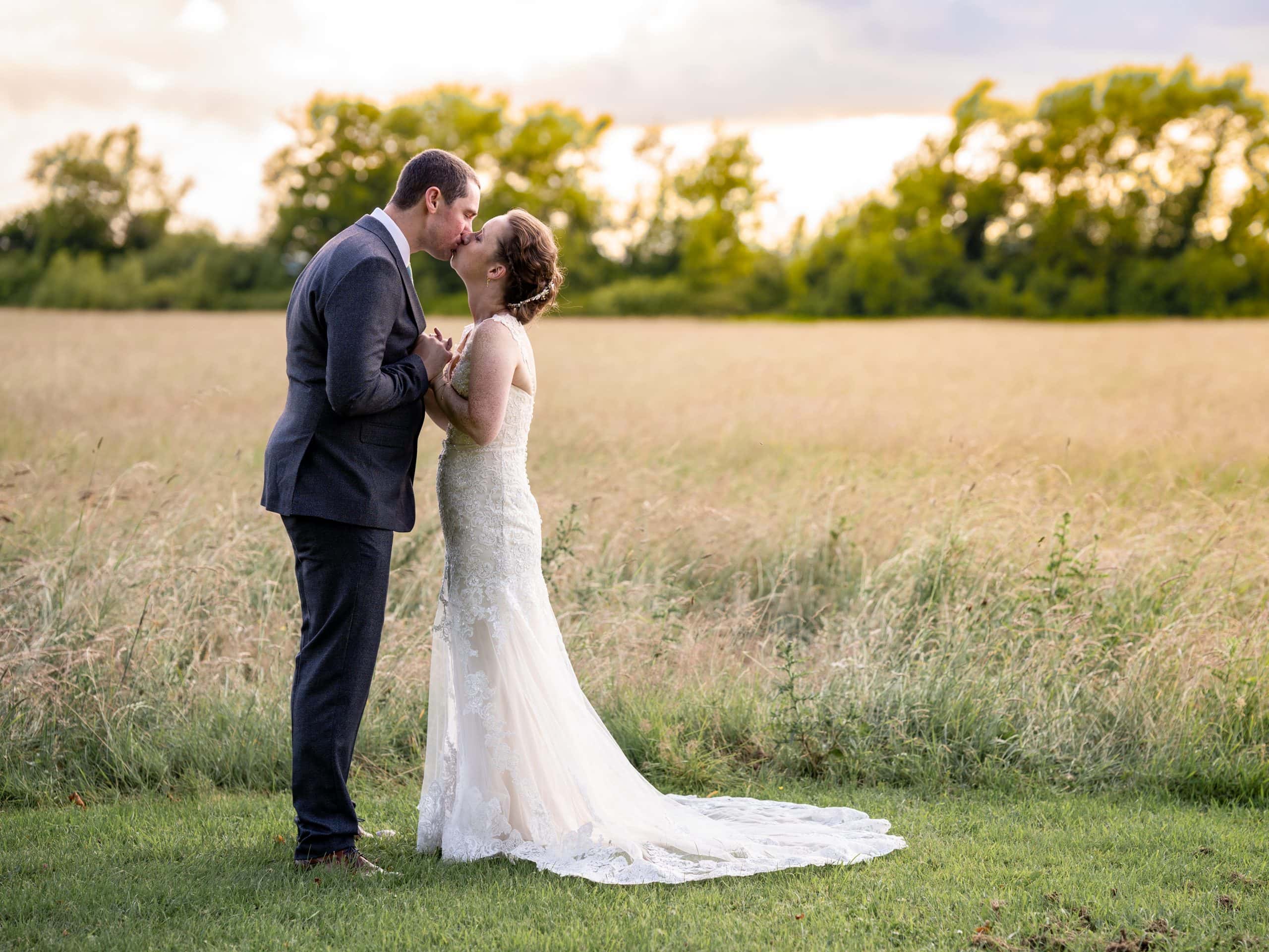Newlywed couple at Hatherley Manor pose in the summer sun of the countryside at Hatherley Manor