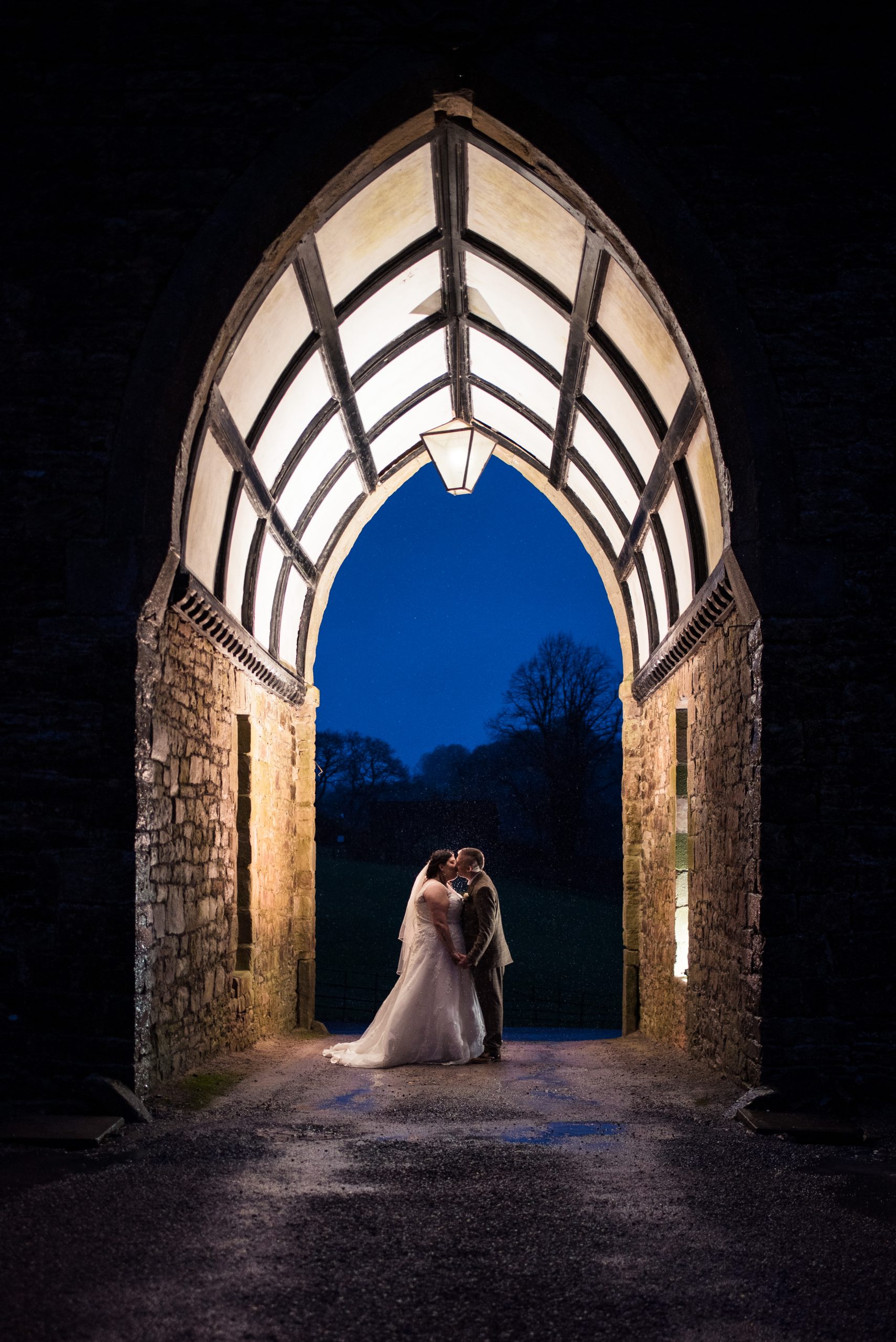 Clearwell Castle has the most gorgeous archaway and when lit up, it provides a stunnnig addition to couple shots on your wedding day. This particular image sees a couple stood in the arch, sharing a kiss and lit up with a flash with a yellow gel over it.