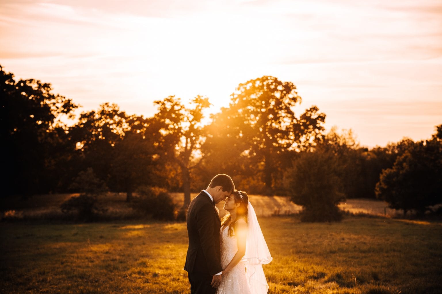 Married couple embrace in the summer sunset of Ellenborough Park Hotel