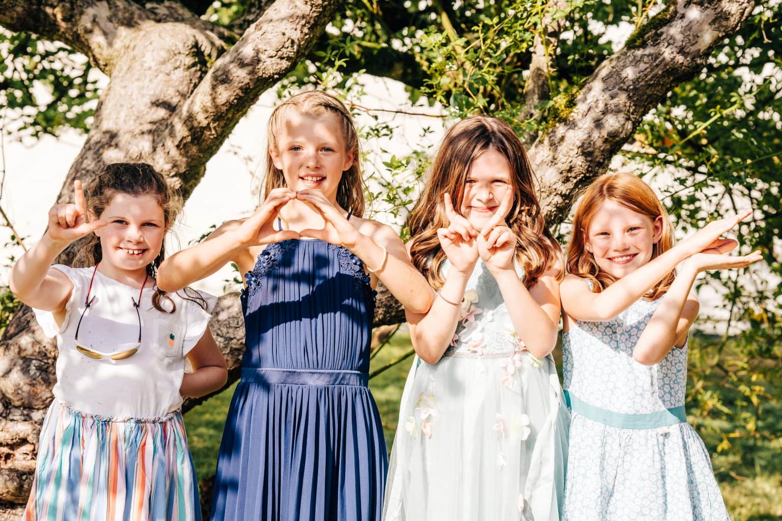 Four young girls posing for Pedge Photograpy by spelling out LOVE with their hands