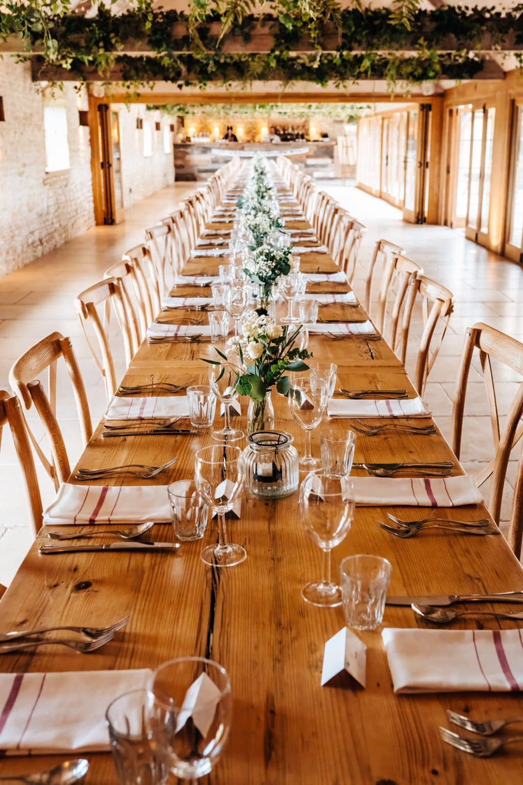 Mediterranean vibes at dining with long tables full of flowers and vines at Old Gore Barn by Yard Space, Cirencester