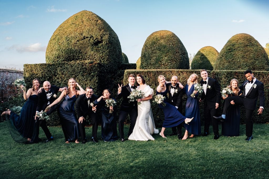 Bride and groom with their immediate wedding party pose for a fun group photo at Worcestershire Wedding Venue Birtsmorton Court