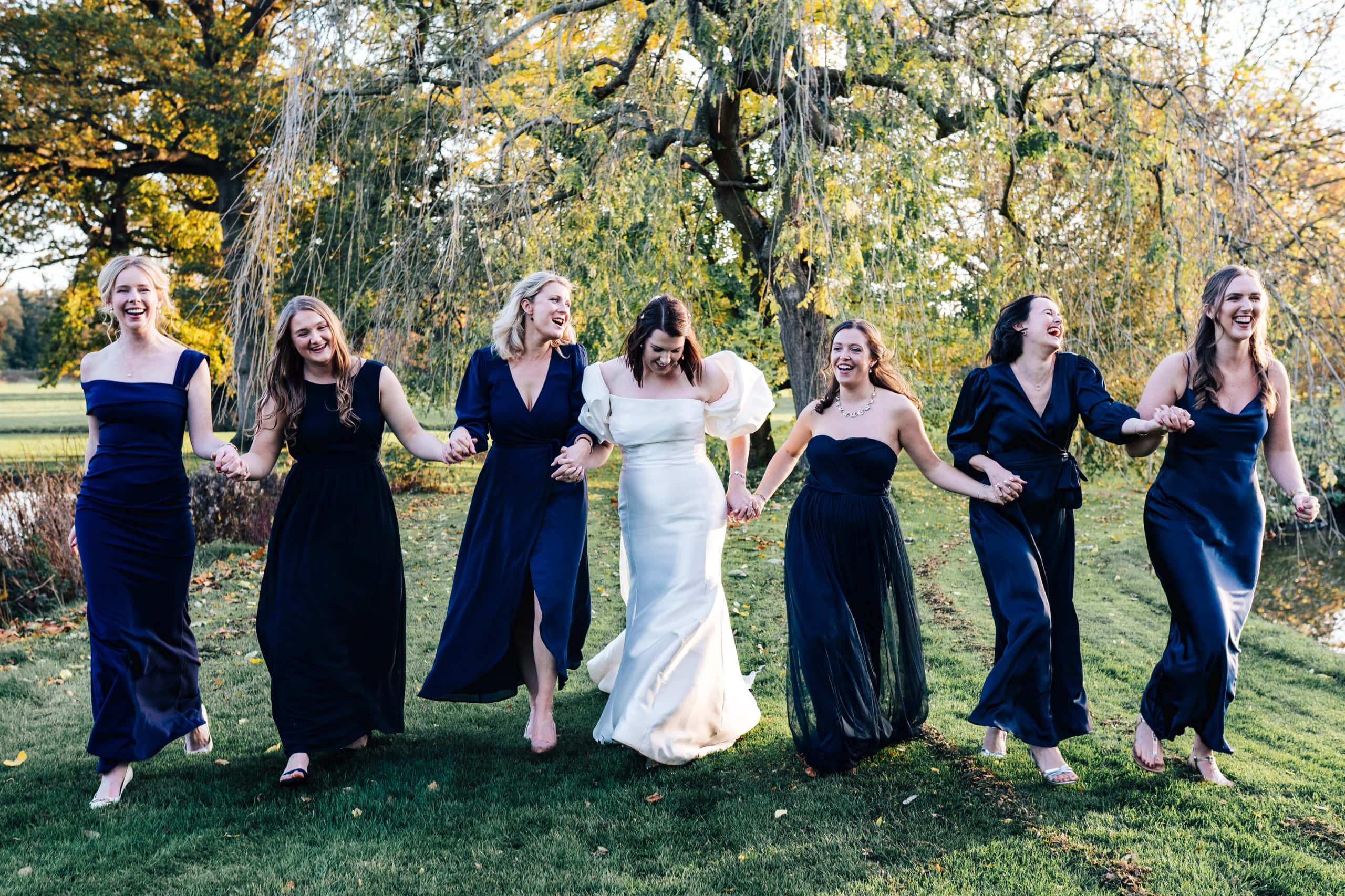 Bridal squad link arms, sing and walk towards the camera in a great effort for a group photo at Worcestershire wedding venue Birtsmorton Court