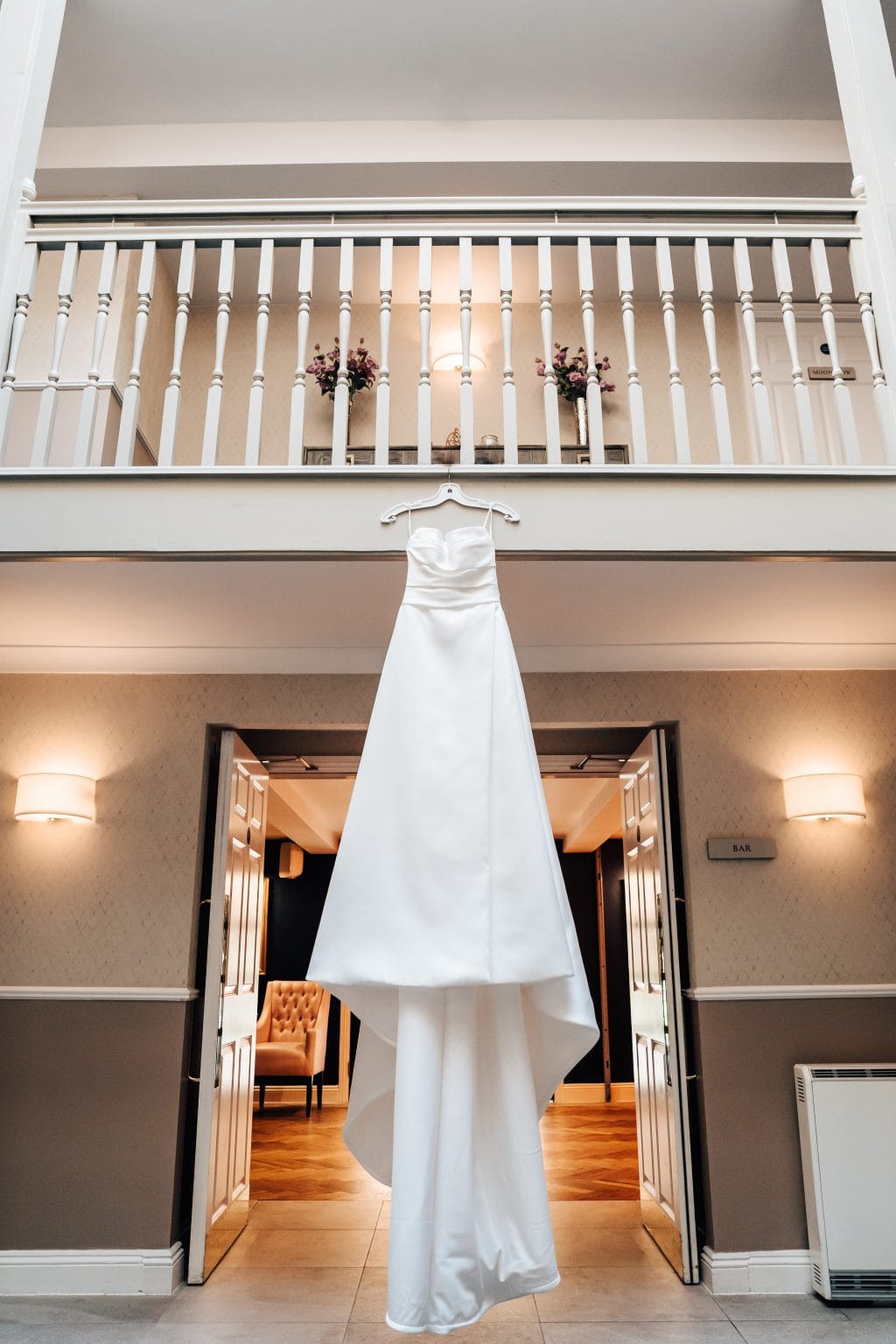 Wedding dress hangs over the stair bannister at The Pear Tree wedding venue in Swindon.