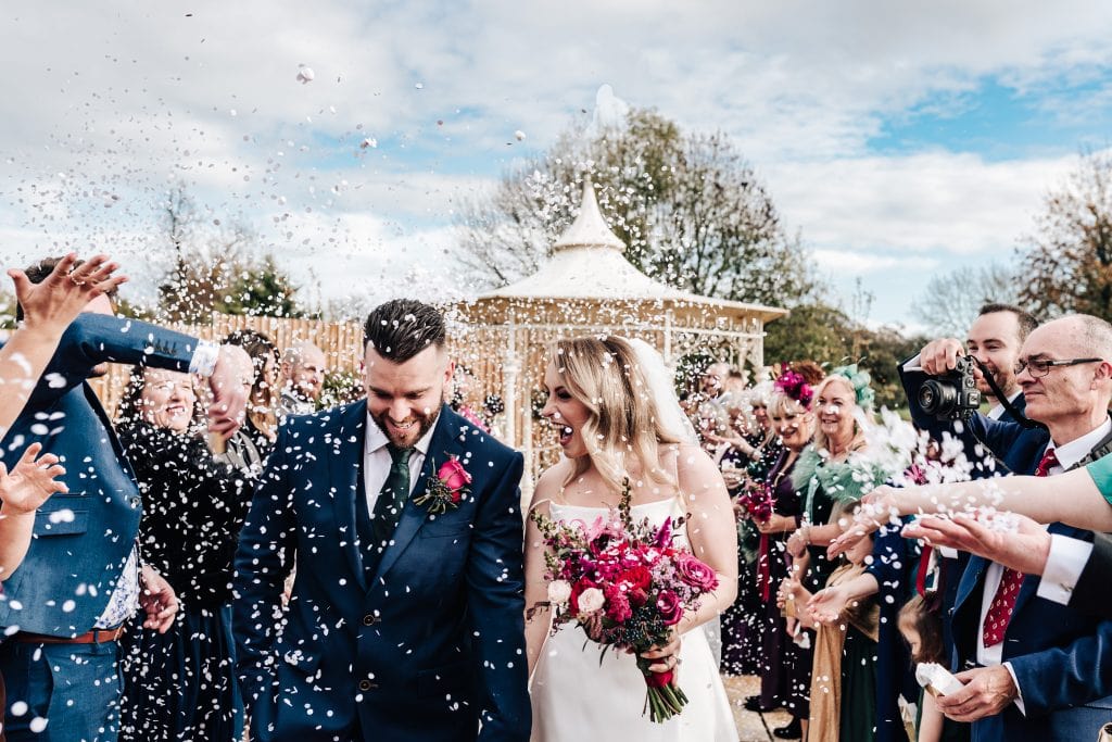 White confetti covers the newly married couple at The Pear Tree in Swindon
