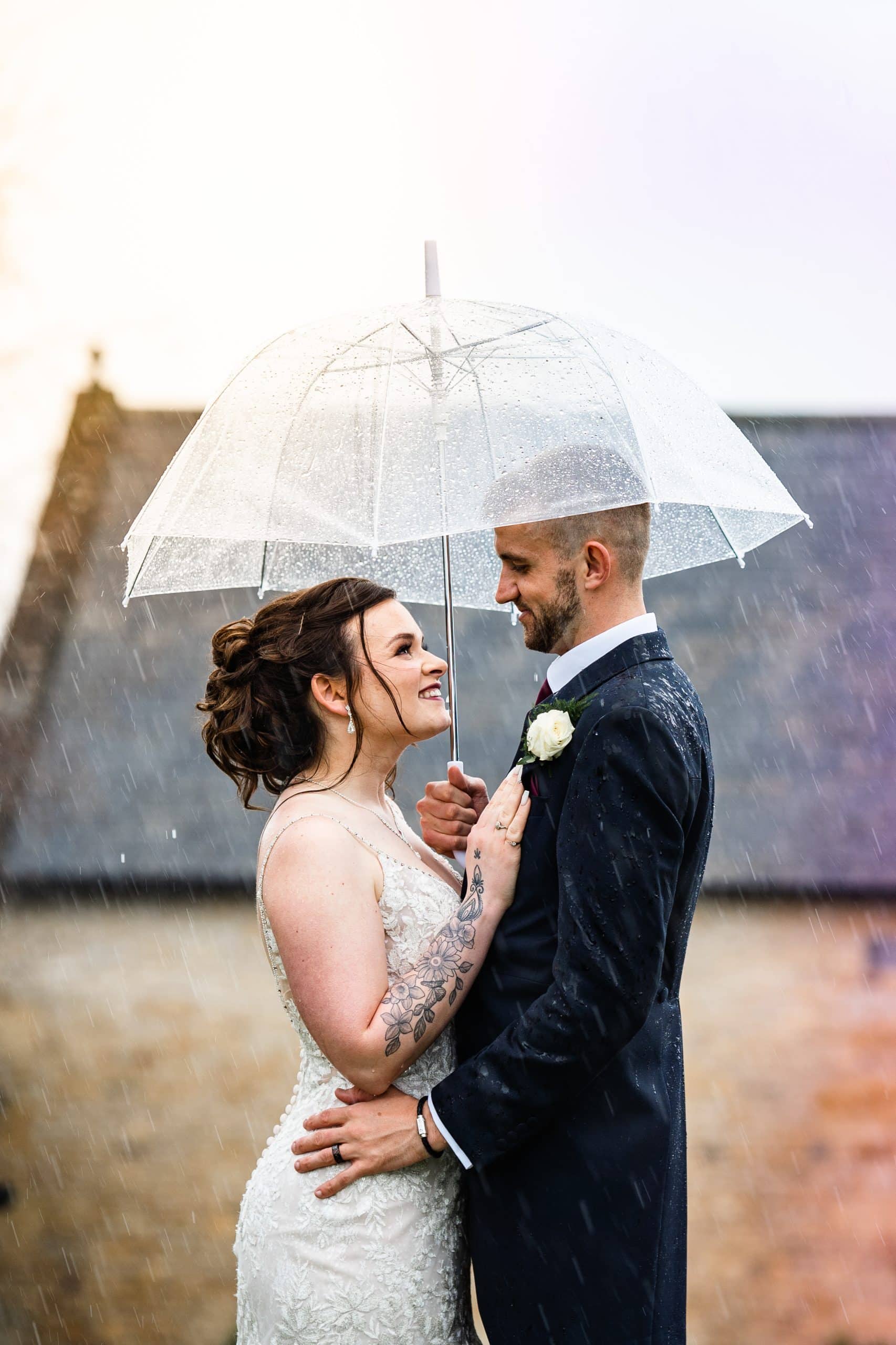 The Barn at Upcote recommended photographer Pedge Photography captures this stunning shot that creatively utilises the downpour of rain that hits Mollie & Matt.